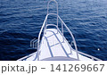 Bow of a white boat with railings moves smoothly across tranquil blue ocean water, reflecting sunlight and creating a peaceful maritime atmosphere 141269667