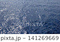Ocean water surface displays sunlight reflections and gentle ripples, creating a tranquil scene with shimmering patterns in a coastal setting 141269669