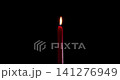 A single red candle burning on a dark, isolated background. This festive candle shines with a bright, clean flame of hope. Perfect candle for stock layouts with blending mode screen or add. 141276949