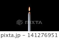 A white candle burning with a sharp and steady flame. Against a dark background, this elegant candle brings a sense of comfort. A timeless candle for Christmas or memorial events. 141276951