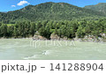 Wide-angle view of the turquoise Katun river flowing rapidly past rocky shores and green forested mountains on a sunny summer day under a clear blue sky, 4k 141288904