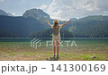 Teenage girl with backpack raising her hands while admiring Black Lake in Durmitor National Park, Montenegro. 141300169