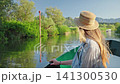 Woman enjoying a peaceful boat ride along the waterways of Skadar Lake in Montenegro surrounded by lush wetlands and mountain scenery. 141300530