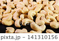 Cashew nuts are scattered across a black background, with grains falling from above. 141310156