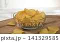 Ridged potato chips in glass bowl, light background, minimal kitchen with soft light 141329585