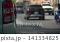 4K video shot focusing on the red tail light of a pickup car. In the background blurred of other cars and motorcycles drive past on a city street lane during a bright daytime commute. 141334825