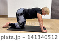 A person performs a series of stretching exercises to enhance flexibility and strength in a fitness studio during a workout session 141340512