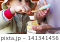 Toddler enjoys vegetable baby food with help from caregiver 141341456