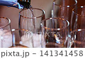 Pouring drinks into glasses at a celebration in a lively space 141341458