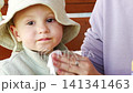 Child enjoys snack time with caregiver outdoors in sunny weather 141341463