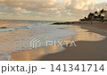 Gentle ocean waves washing onto a wide sandy beach at sunset 141341714