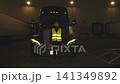 Truck driver standing proudly in front of a semi-truck at night 141349892