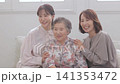 A three-generation family of women sitting on a sofa A three-generation family of women sitting on a sofa 141353472