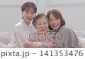 A three-generation family of women sitting on a sofa A three-generation family of women sitting on a sofa 141353476