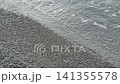 Waves wash over a pebbled beach, creating a soothing rhythm as they recede, highlighting the natural beauty of the shoreline and water interaction 141355578