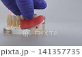 Dentist hand in blue glove removing dental bridge from implant jaw model. Dental prosthetics concept with copy space 141357735