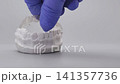 Dentist hand in blue glove placing clear orthodontic aligner onto lower plaster dental model. Invisible braces concept with copy space 141357736