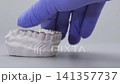 Dentist hand in blue glove fitting clear orthodontic aligner onto plaster dental model. Invisible braces concept with copy space 141357737