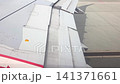 Aircraft wing with extended flaps and slats visible during taxiing on runway, showcasing mechanical components and surface details in a clear sky environment 141371661