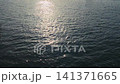 Sunlight reflecting on calm water surface, showcasing gentle ripples and shimmering patterns in a serene outdoor setting near a body of water 141371665