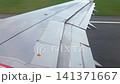 Aircraft wing view showing flaps in motion during landing approach, highlighting aerodynamic components and runway markings in the background 141371667