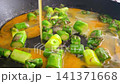 Fresh green asparagus pieces sauteed in a frying pan with cracked eggs pouring in, creating a vibrant mixture of colors and textures in a kitchen setting 141371668