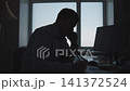 Silhouetted office worker holding corded phone beside large desk in backlit workspace with window glow, focused professional mood, serious posture, modern corporate interior 141372524