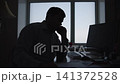 Silhouetted office worker speaking on telephone and taking notes at desk with strong backlit window 141372528