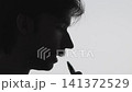 Relaxed side profile silhouette of man smoking cigarette against neutral background with clean natural light, strong contrast, minimal composition, commercial concept, calm atmosphere 141372529