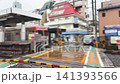 A pink train of the Keio Inokashira line arrives at Shimokitazawa station in Setagaya district during a rainy spring day in April. The railway crossing barrier is lowered and the warning lights. 141393566