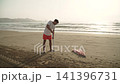 Man installing beach umbrella pole and screwing it into sandy beach. Taking spot on seaside resort coast early morning. Protection from ultraviolet. 141396731