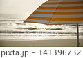Beach umbrella with orange and white stripes in backlight against splashing sea waves. Background video of beach season, rest and vacation without people. 141396732