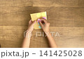 A child's hand putting a pink circular sticker back onto the backing after peeling it off the backing (4K silent video) 141425028