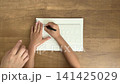 Child's hand drawing a circle in a sketchbook using a pattern template and a black pen (4K) 141425029