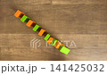 A child's hands playing dominoes by arranging light green and orange building blocks diagonally (4K) 141425032
