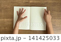 A child's hand holds the notebook with its left hand and traces the lines with the fingers of its right hand (4K). 141425033