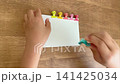 A child's hand clipping a sixth color clip onto a piece of white paper (4K) 141425034