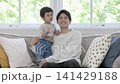 A little boy cuddling with his dad on the sofa at home. A little boy cuddling with his dad on the sofa at home. 141429188