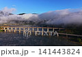 Fog covers a river and bridge during early morning hours in a scenic landscape with mountains in the background 141443824