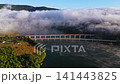 Bridge connects land across river while clouds cover mountains during dawn in a rural area 141443825