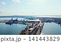 Bright day at the busy port with ships and cargo containers near the water and distant hills in the background 141443829