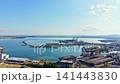View of a busy port with ships and cranes, showing industrial activity near water during a clear day with few clouds 141443830