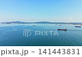 Ships are anchored in the water near the shore with distant hills under a clear blue sky during daytime 141443831
