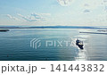 Large cargo ship navigates through calm waters near a coastal area during midday with clear skies in the background 141443832