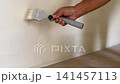 Hand Touch Up Painting Uneven White Wall With Paintbrush 141457113