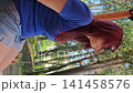 Beautiful young woman enjoys time on a swing in a park during the day 141458576