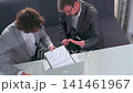 Businessmen intensely reviewing and discussing contract details in modern office 141461967