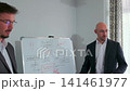 Two businessmen discussing business strategy at whiteboard 141461977