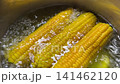 Boiling three ears of corn in a saucepan. 141462120
