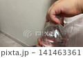 Close up view of little child hand unscrewing cap of clear plastic water bottle for healthy hydration daily habit and refreshment drink concept 141463361